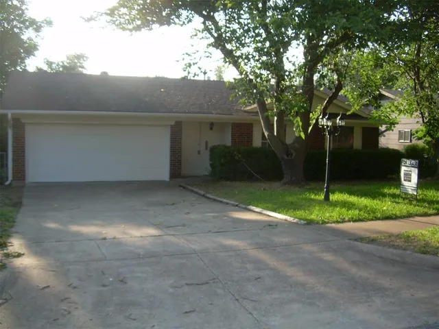 a view of a house with a yard and large tree