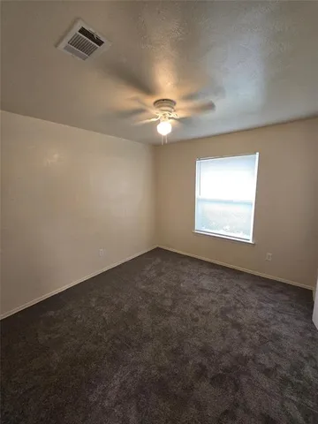 an empty room with windows and fan
