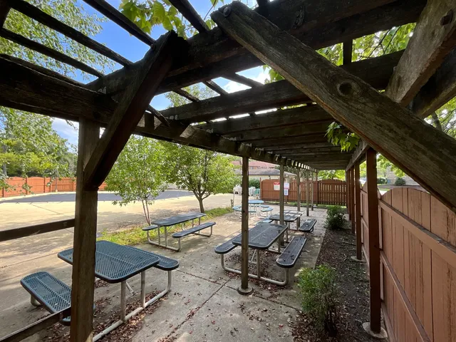 a view of a chairs and table in the patio next to a yard