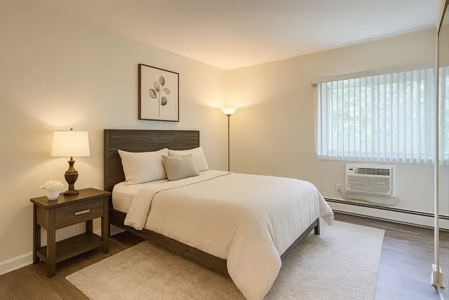 a bedroom with a bed and a lamp on dresser