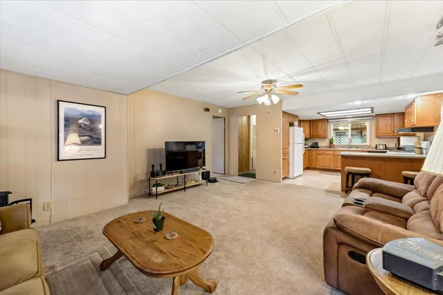 a living room with furniture a flat screen tv and kitchen view