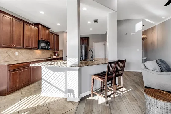 a kitchen with stainless steel appliances kitchen island granite countertop a stove a sink a microwave a refrigerator and cabinets