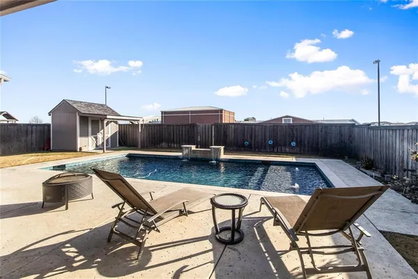 a swimming pool with outdoor seating and yard in the back
