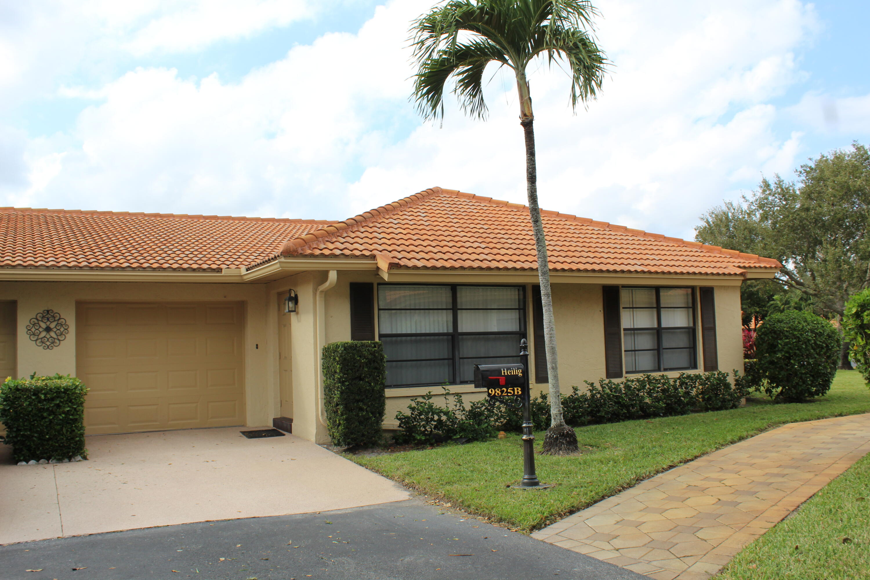9825 Bischofia Tree Way, Unit B Boynton Beach, FL 33436 - Photo 1 of 12 a front view of a house with a garden and trees