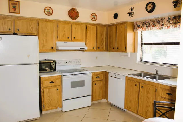 a kitchen with a sink a stove a refrigerator and a window