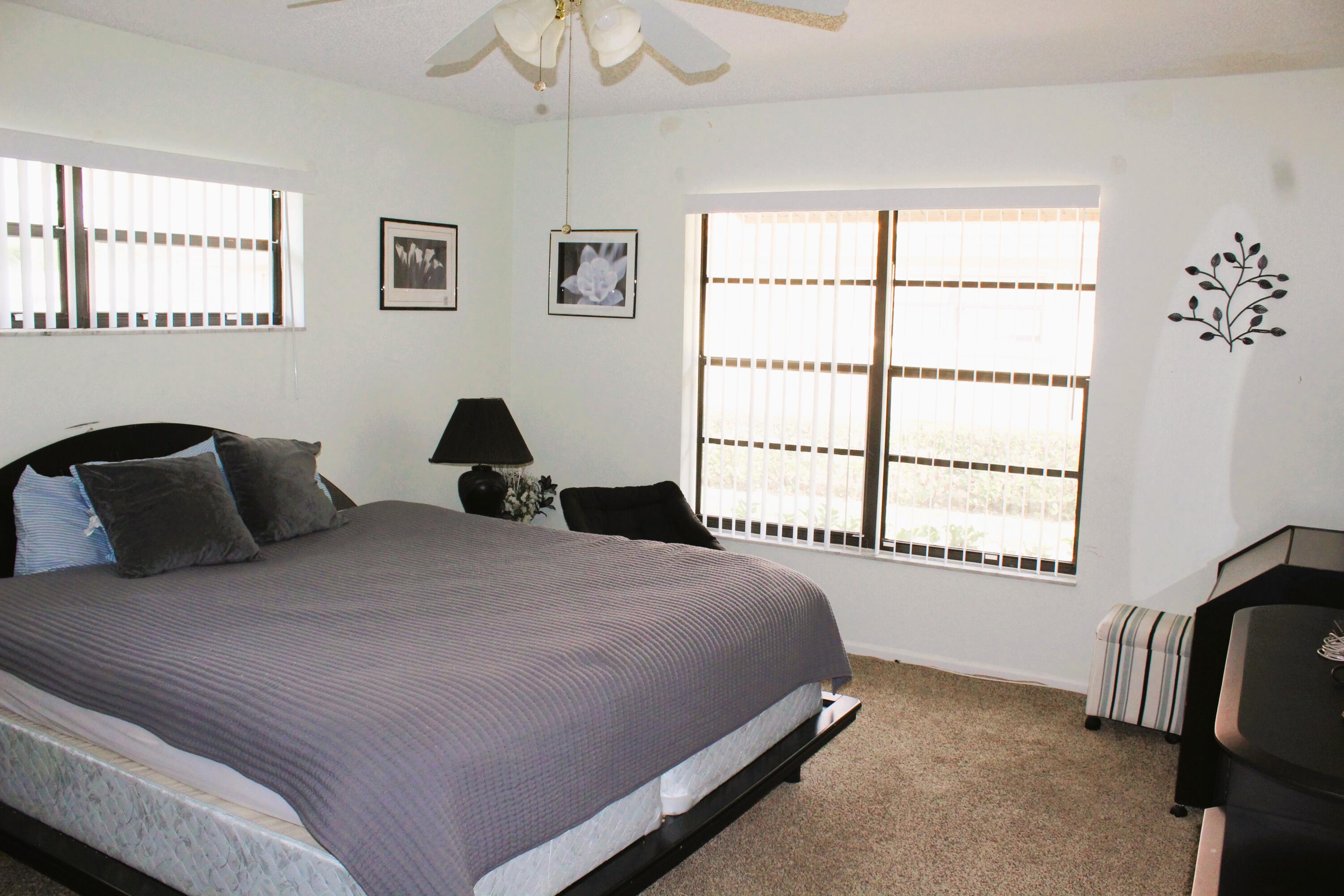 9825 Bischofia Tree Way, Unit B Boynton Beach, FL 33436 - Photo 7 of 12 a bedroom with a bed lamp and a window
