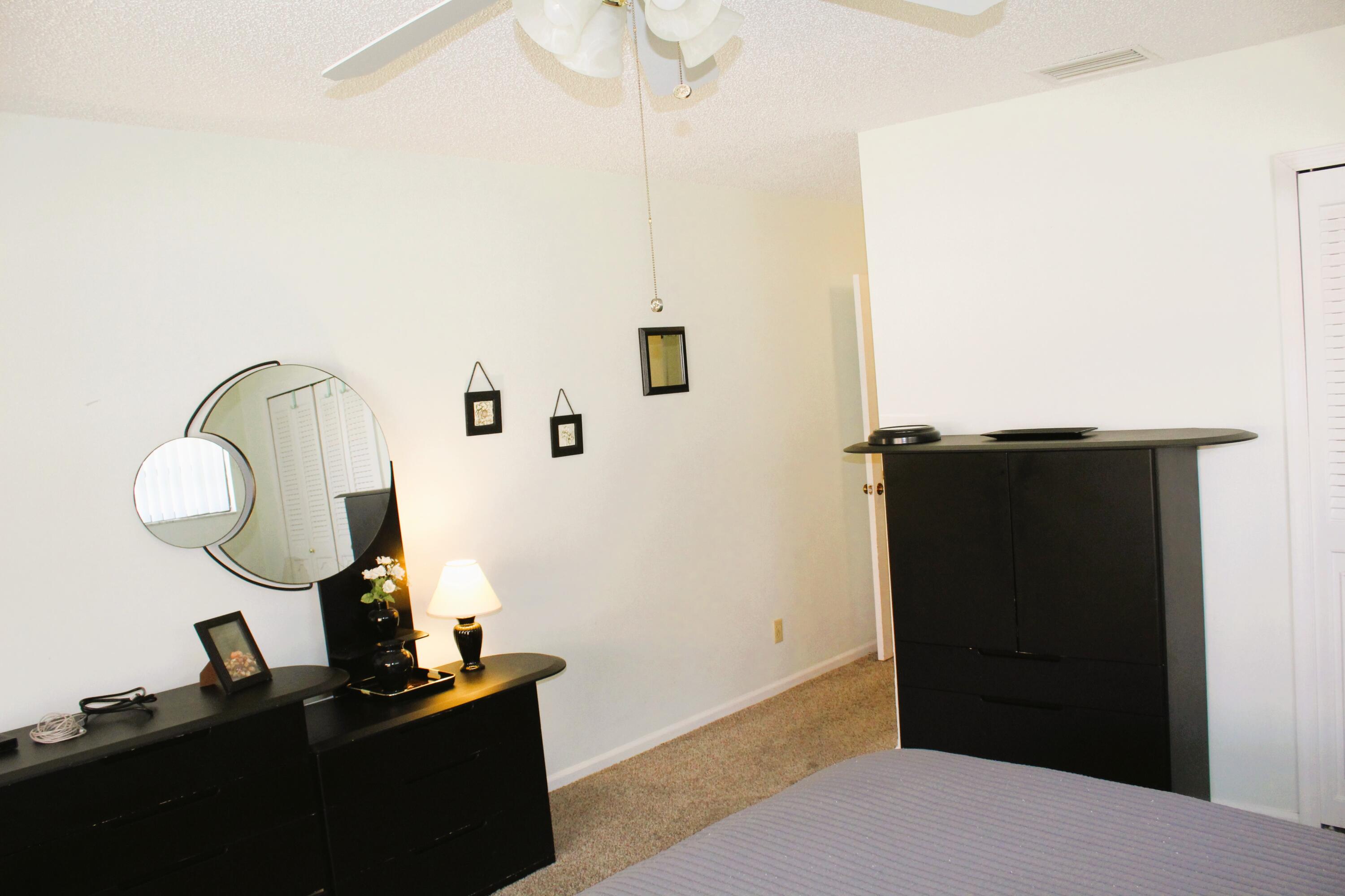 9825 Bischofia Tree Way, Unit B Boynton Beach, FL 33436 - Photo 8 of 12 a bedroom with a bed and a mirror