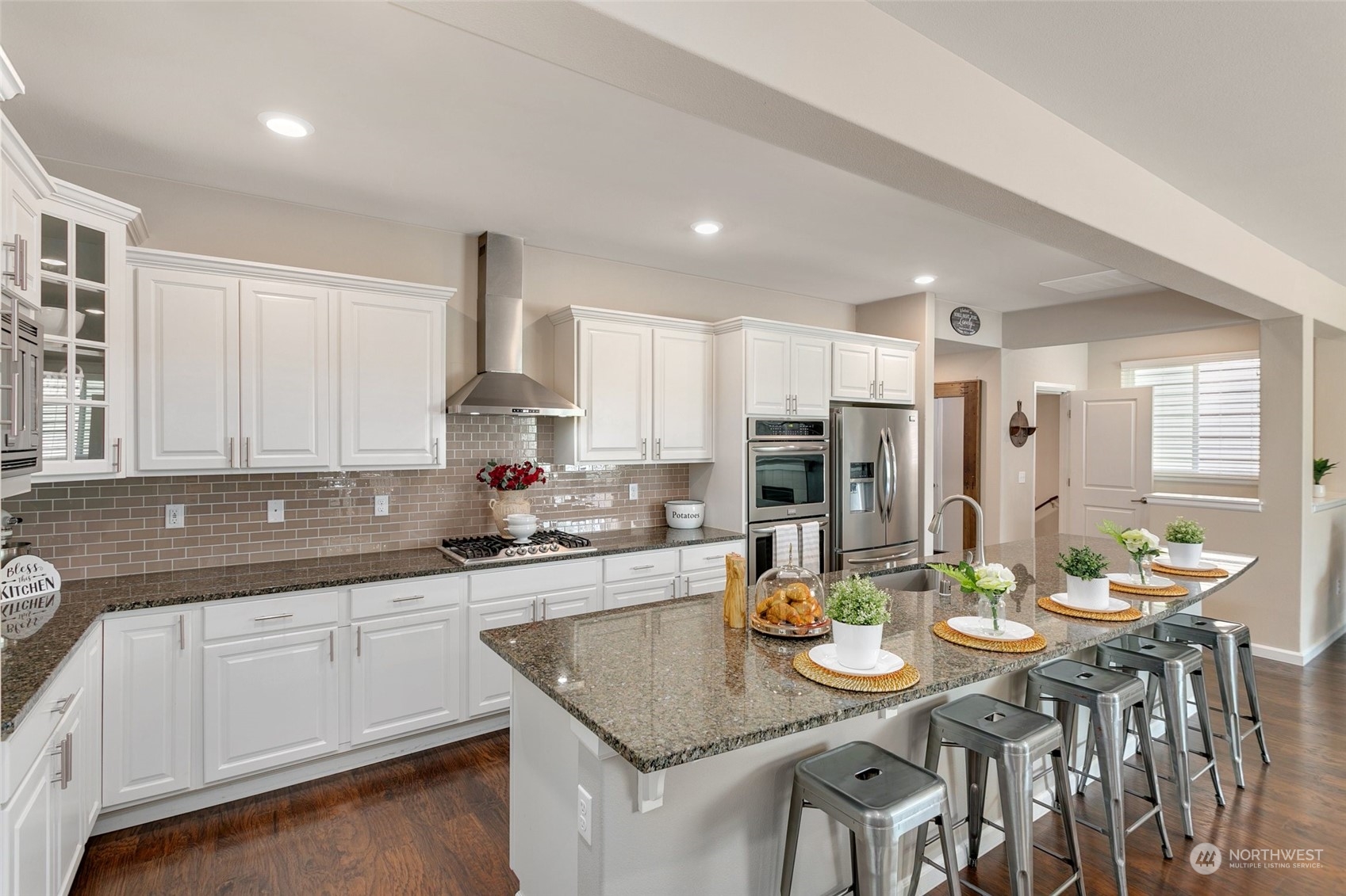 15931 Meridian Avenue South Bothell, WA 98012 - Photo 8 of 40 a kitchen with stainless steel appliances granite countertop a sink a stove a kitchen island with chairs and white cabinets
