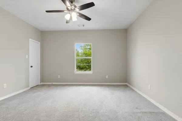 an empty room with a window and a fan