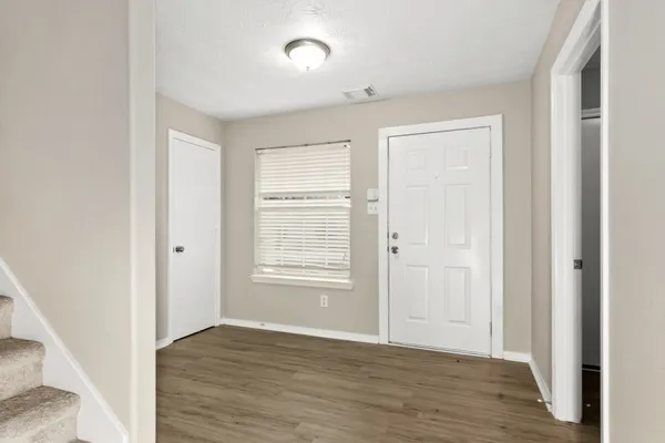 an empty room with wooden floor and windows