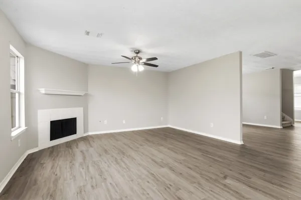 an empty room with wooden floor fireplace and windows
