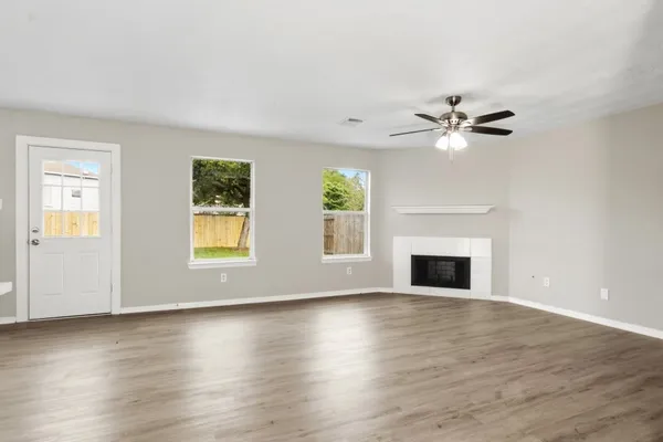 an empty room with windows fireplace and wooden floor