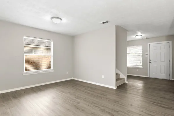 an empty room with wooden floor and windows