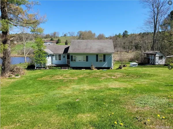 a view of a house with a big yard and large trees