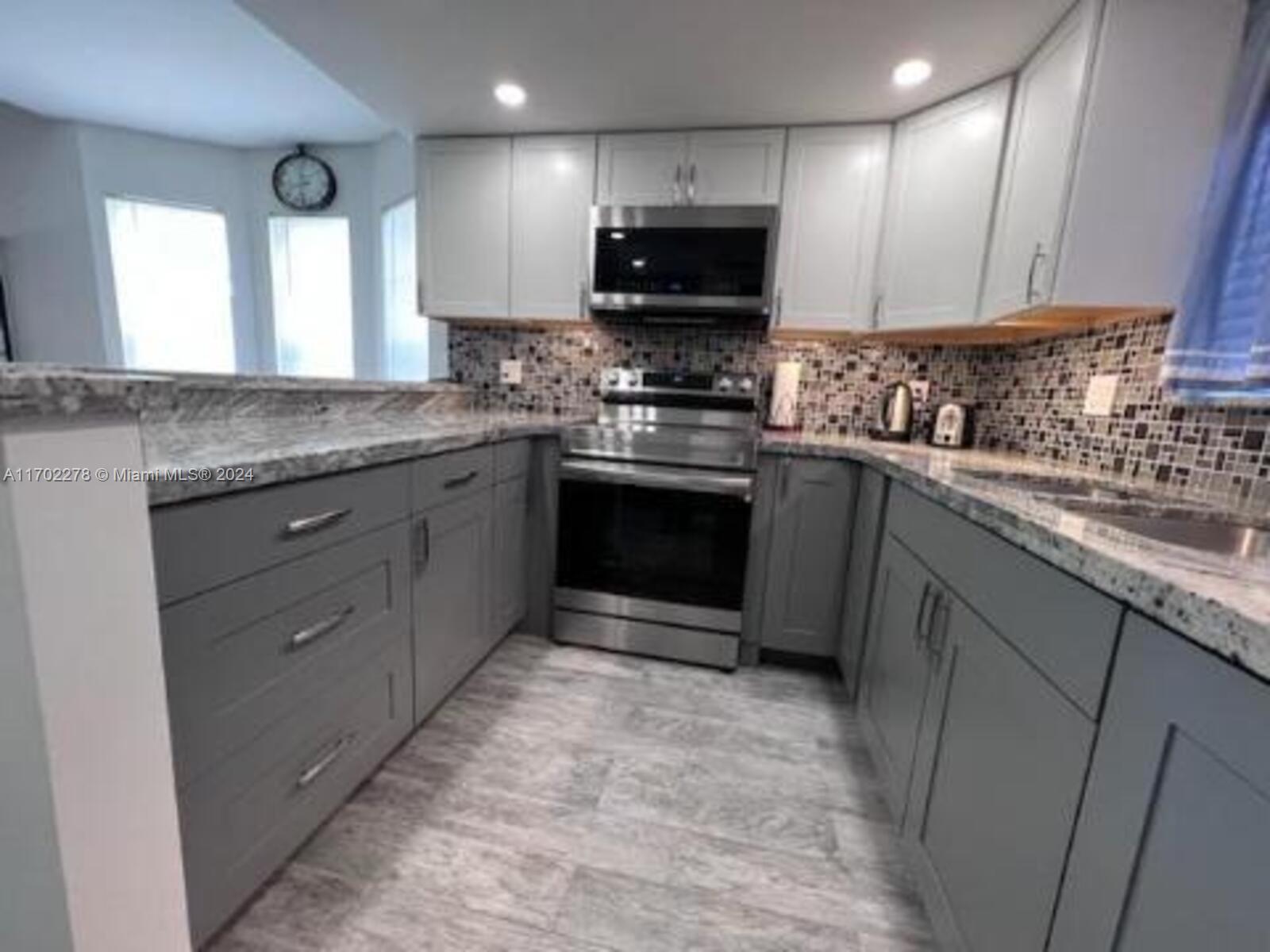 6299 La Costa Drive, Unit D Boca Raton, FL 33433 - Photo 11 of 23 a kitchen with stainless steel appliances granite countertop a stove a sink and a microwave