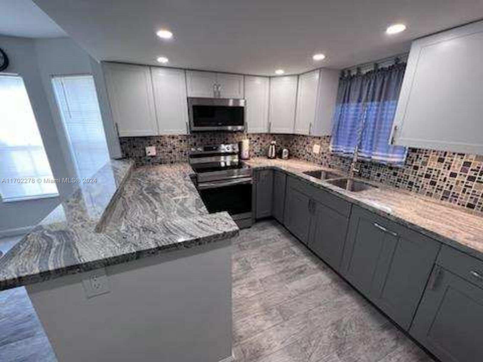 6299 La Costa Drive, Unit D Boca Raton, FL 33433 - Photo 9 of 23 a kitchen with kitchen island granite countertop stainless steel appliances a sink a stove a microwave a refrigerator and cabinets