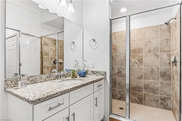 a bathroom with a granite countertop sink a mirror and shower