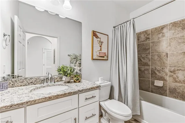 a bathroom with a granite countertop sink a toilet and shower
