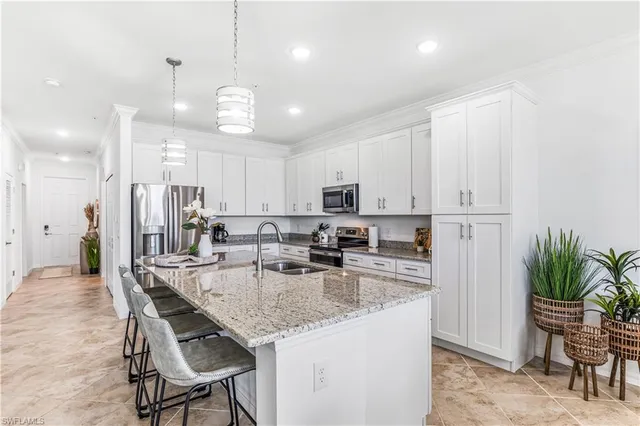 a kitchen with kitchen island granite countertop stainless steel appliances a refrigerator a stove a sink a dining table and chairs with wooden floor