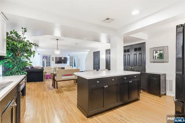 a living room with stainless steel appliances kitchen island granite countertop a sink and wooden floor