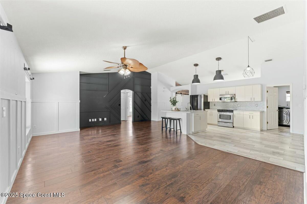 194 Saybrook Road Southwest Palm Bay, FL 32908 - Photo 18 of 35 a view of a living room and kitchen with furniture and wooden floor