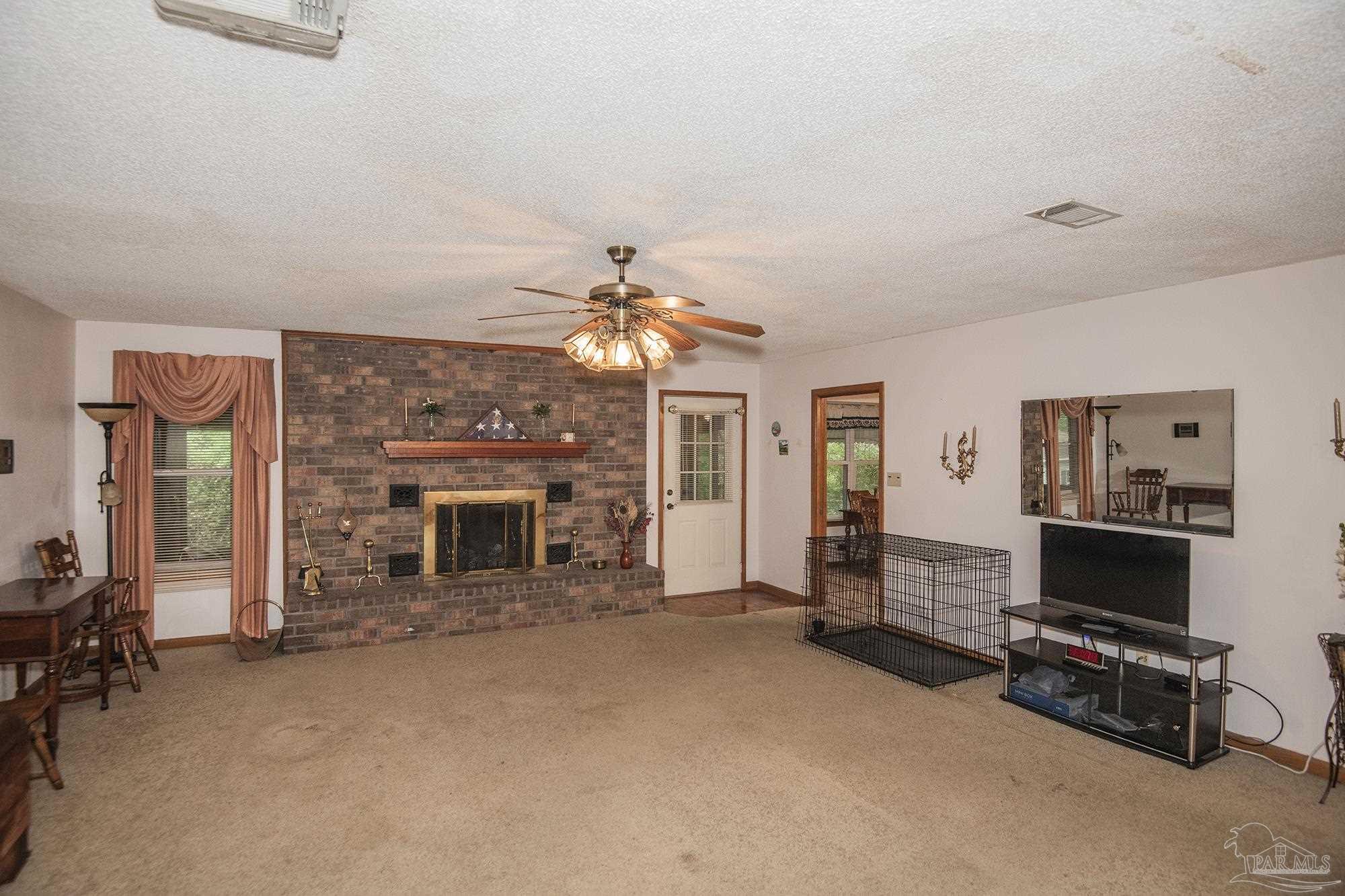 1210 Goldenrod Road Cantonment, FL 32533 - Photo 11 of 50 a view of a livingroom with a fireplace a desk and chair