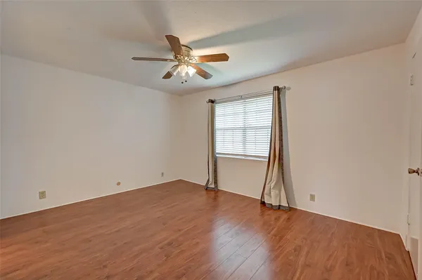 an empty room with wooden floor fan and windows