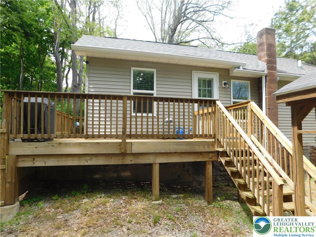 41 Reeder Street Mount Pocono, PA 18344 - Photo 7 of 41 A spacious wooden deck extends from the residence, providing an inviting outdoor living area with stairs descending to the yard.