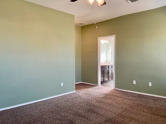 an empty room with a chandelier fan and windows