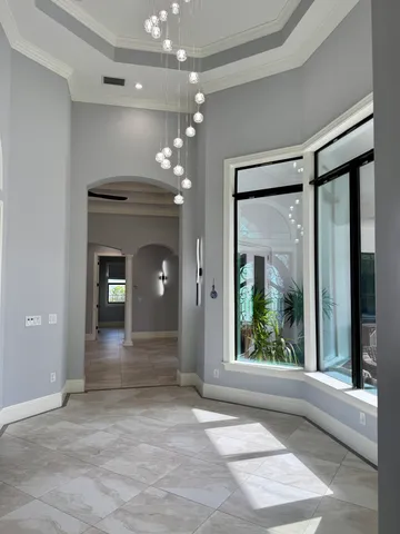 a view of a hallway with a chandelier fan and windows