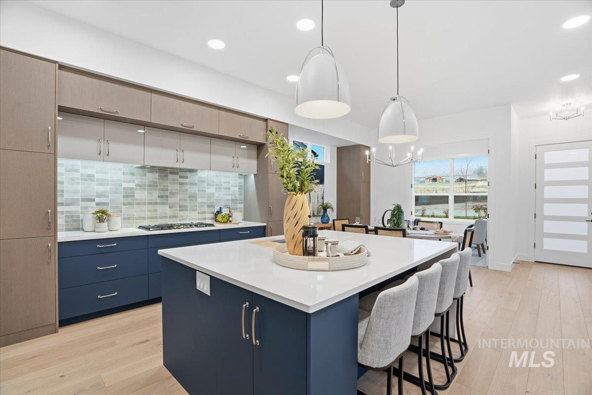 11701 North Rabbitbrush Way Boise, ID 83714 - Photo 16 of 33 Kitchen featuring blue cabinetry, decorative light fixtures, backsplash, light wood finished floors, and recessed lighting