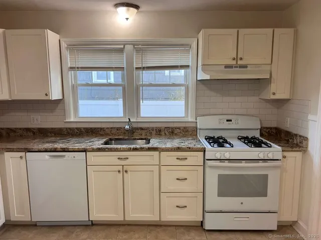 a kitchen with granite countertop white cabinets and white appliances