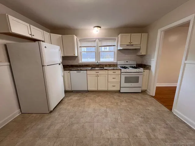 a kitchen with granite countertop a refrigerator stove and sink