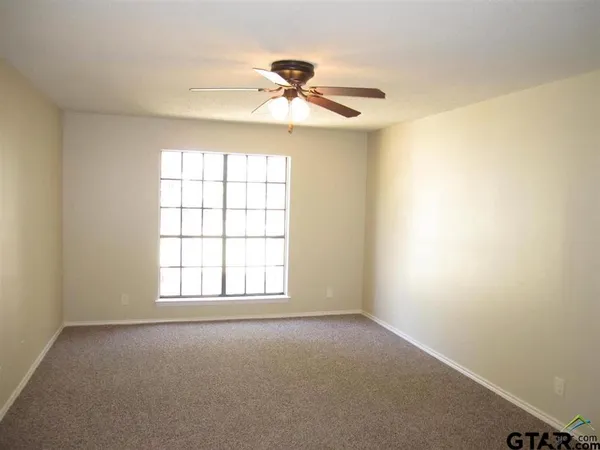 an empty room with a window and a fan