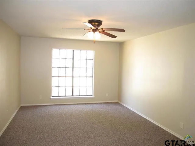 an empty room with a window and a fan