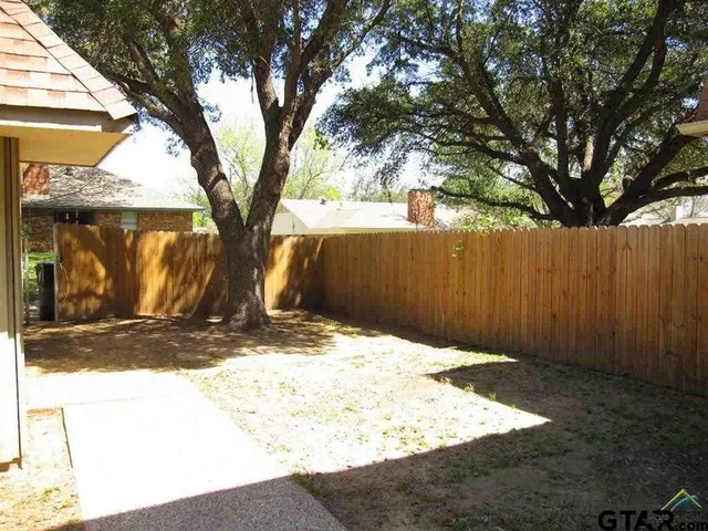 a view of a yard with wooden fence and a large tree