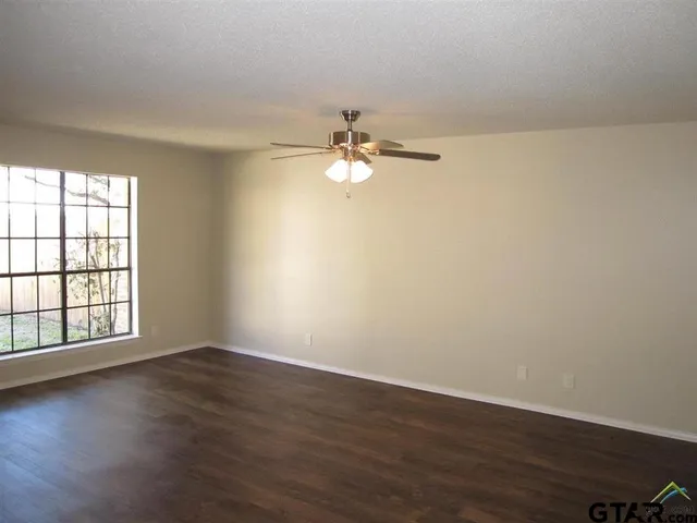 a view of a room with wooden floor and a ceiling fan