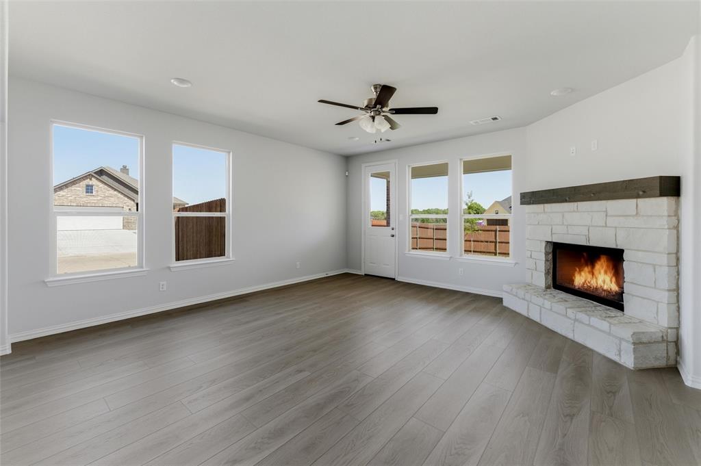 1221 Sabine River Lane Springtown, TX 76082 - Photo 8 of 25 Unfurnished living room featuring a fireplace, ceiling fan, and dark wood-style floors