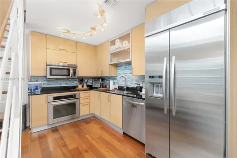 a kitchen with stainless steel appliances granite countertop a refrigerator a stove and a sink