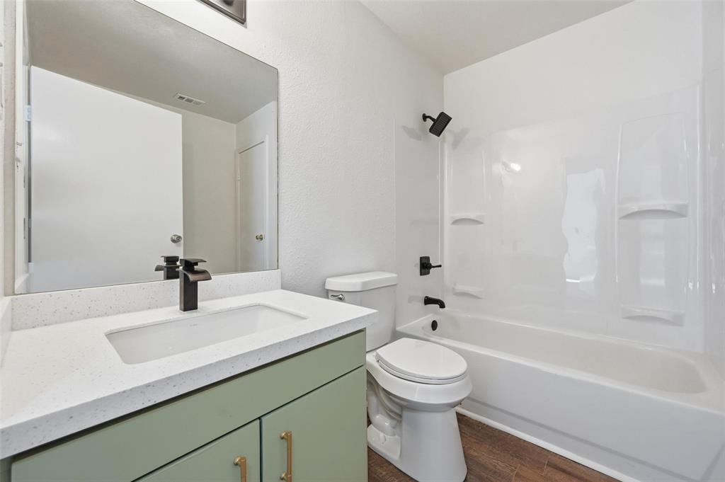 704 Graham Street Cleburne, TX 76033 - Photo 14 of 18 a bathroom with a bathtub shower sink vanity mirror and toilet