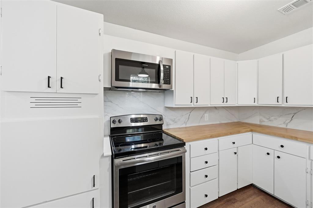 704 Graham Street Cleburne, TX 76033 - Photo 6 of 18 a kitchen with white cabinets and stainless steel appliances