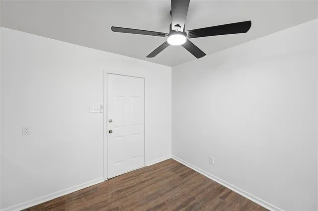 an empty room with wooden floor closet and fan