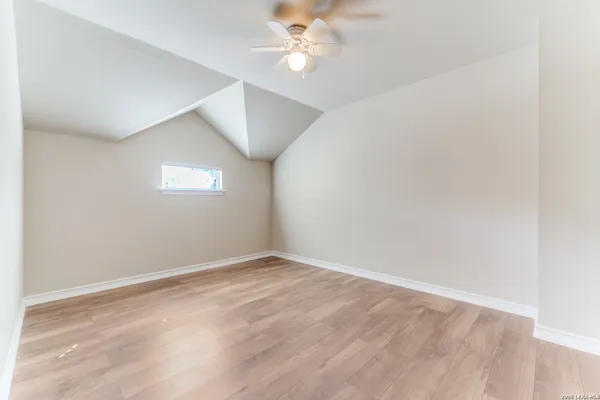 an empty room with a fan & a window