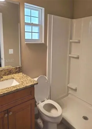 a bathroom with a granite countertop sink toilet and a mirror
