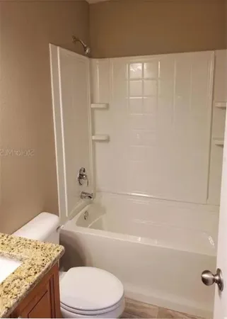 a bathroom with a granite countertop bathtub toilet and sink