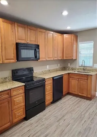 a kitchen with granite countertop wooden cabinets appliances and a window