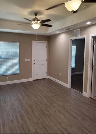 a view of an empty room with wooden floor and a window