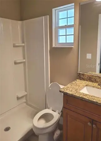 a bathroom with a granite countertop sink toilet and shower