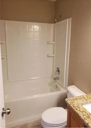a bathroom with a granite countertop bathtub toilet and sink