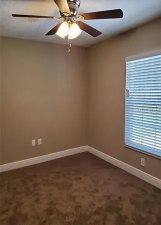 an empty room with a window and a fan